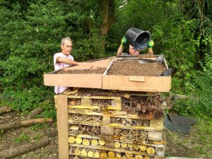 Volunteers filling the bug hotel roof with soil