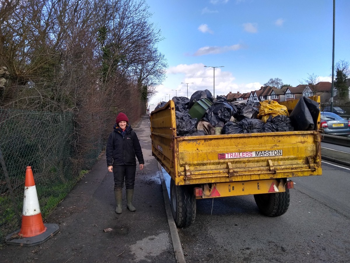 Volunteer next to trailer full of collected litter